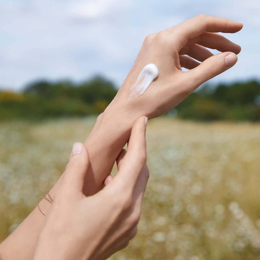 manos femeninas aplicando crema